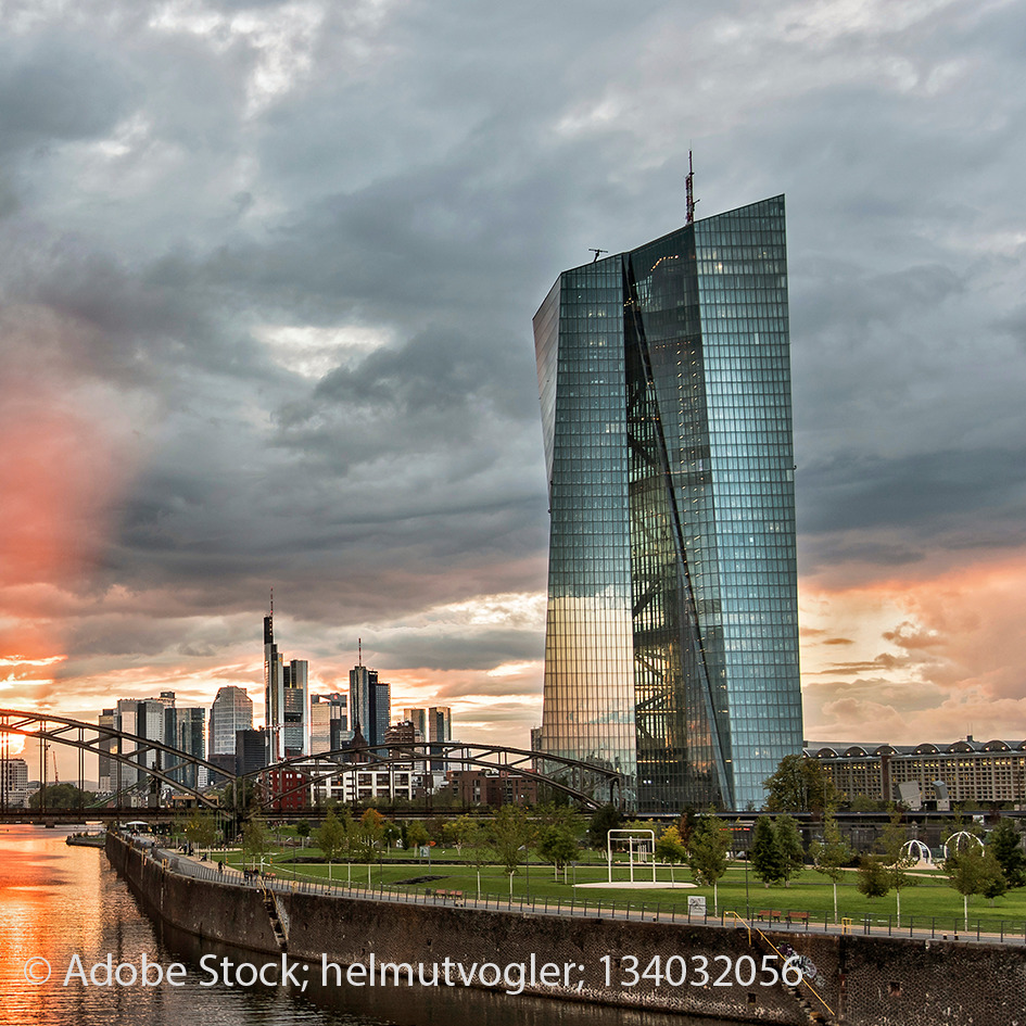 Die Europäische Zentralbank (EZB) in Frankfurt am Main im Sonnenuntergang. Im Vordergrund ist der Main zu sehen.