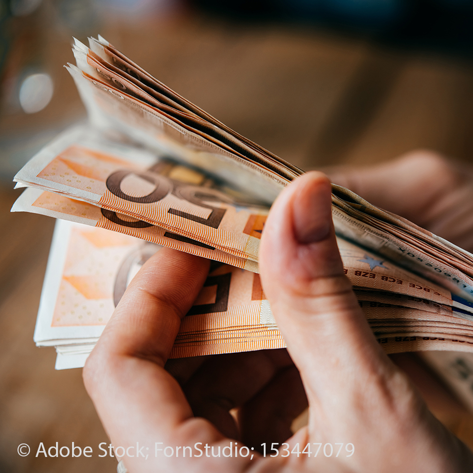 Eine Hand in Nahaufnahme. Sie hält zahlreiche 50-Euro-Banknoten in der Hand.