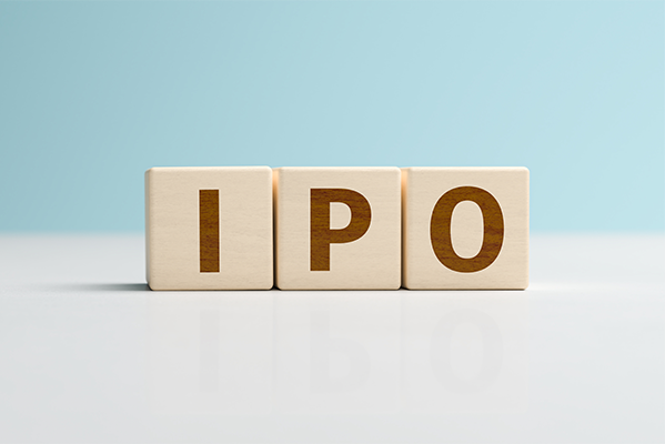 Drei Würfel mit der Aufschrift "IPO" auf einer weißen Fläche vor einem blauen Hintergrund. 