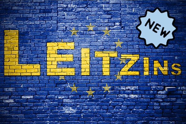 Der Begriff "Leitzins" in gelber Schrift auf einer blauen Backsteinwand. Rundherum die Sterne der Europaflagge.